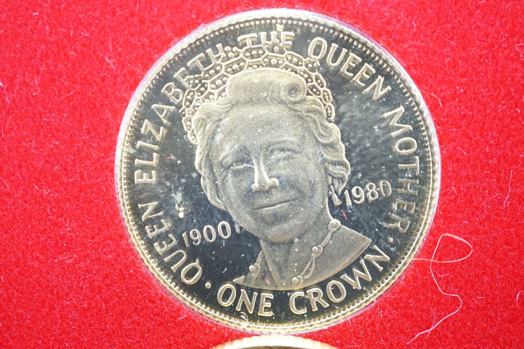 A Victoria 1872 gold sovereign and a Queen Mother 80th Birthday commemorative gold One Crown.